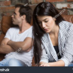 stock-photo-sad-pensive-young-girl-thinking-of-relationships-problems-sitting-on-sofa-with-offended-boyfriend-1034150995